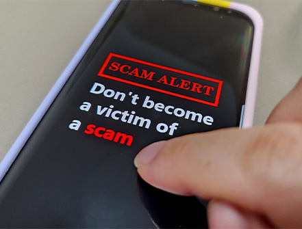 A person gets a bank notice warning against scams by text and email on their mobile device.