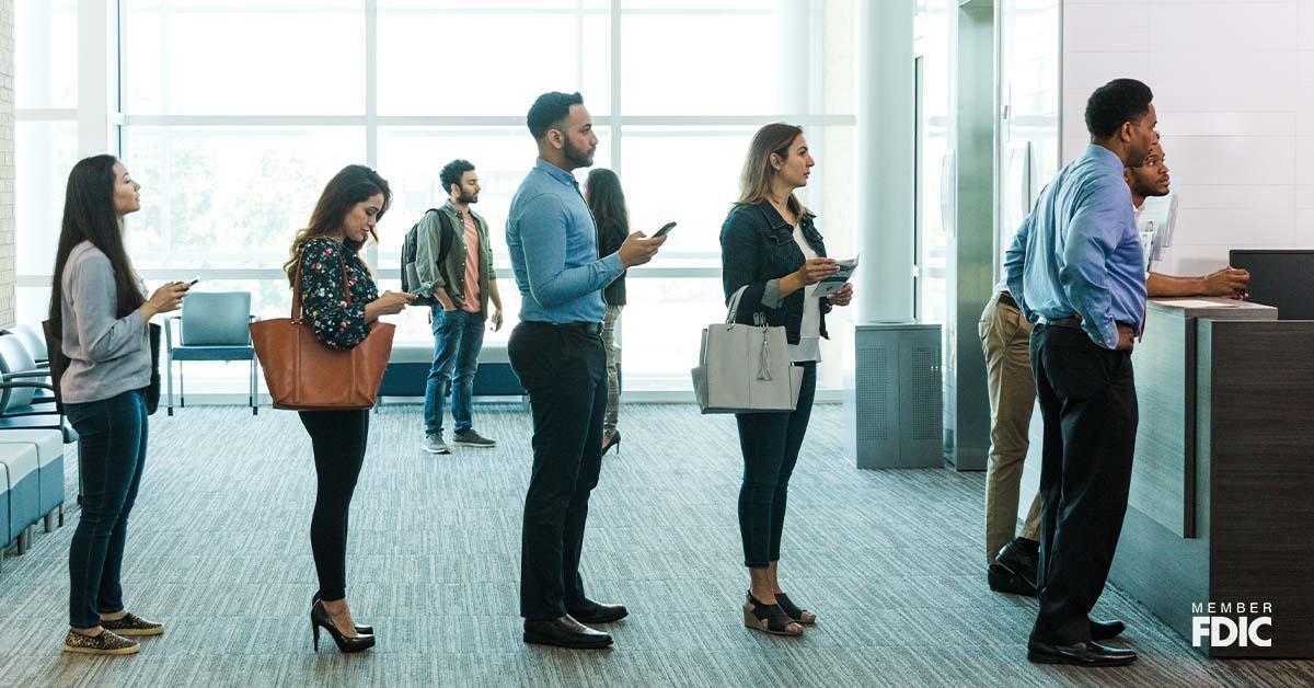 Bank customers form a line to see a bank teller and learn more about special rates. 